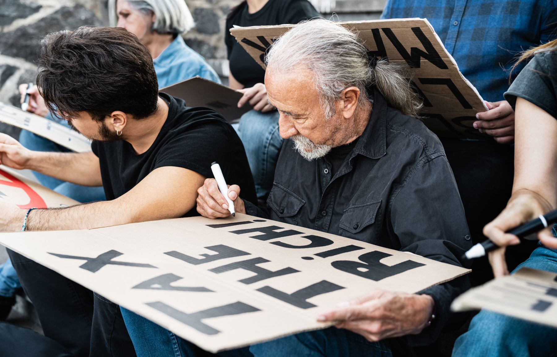 Man making a sign saying tax the rich
